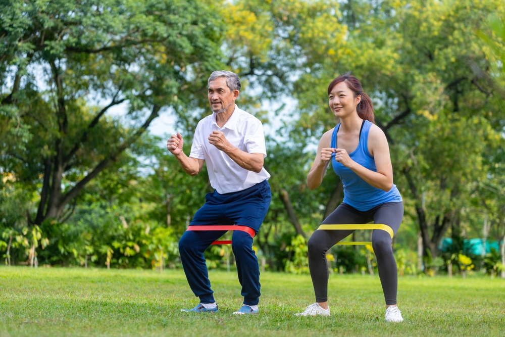 Senior Asian man and his daughter using a resistance band together